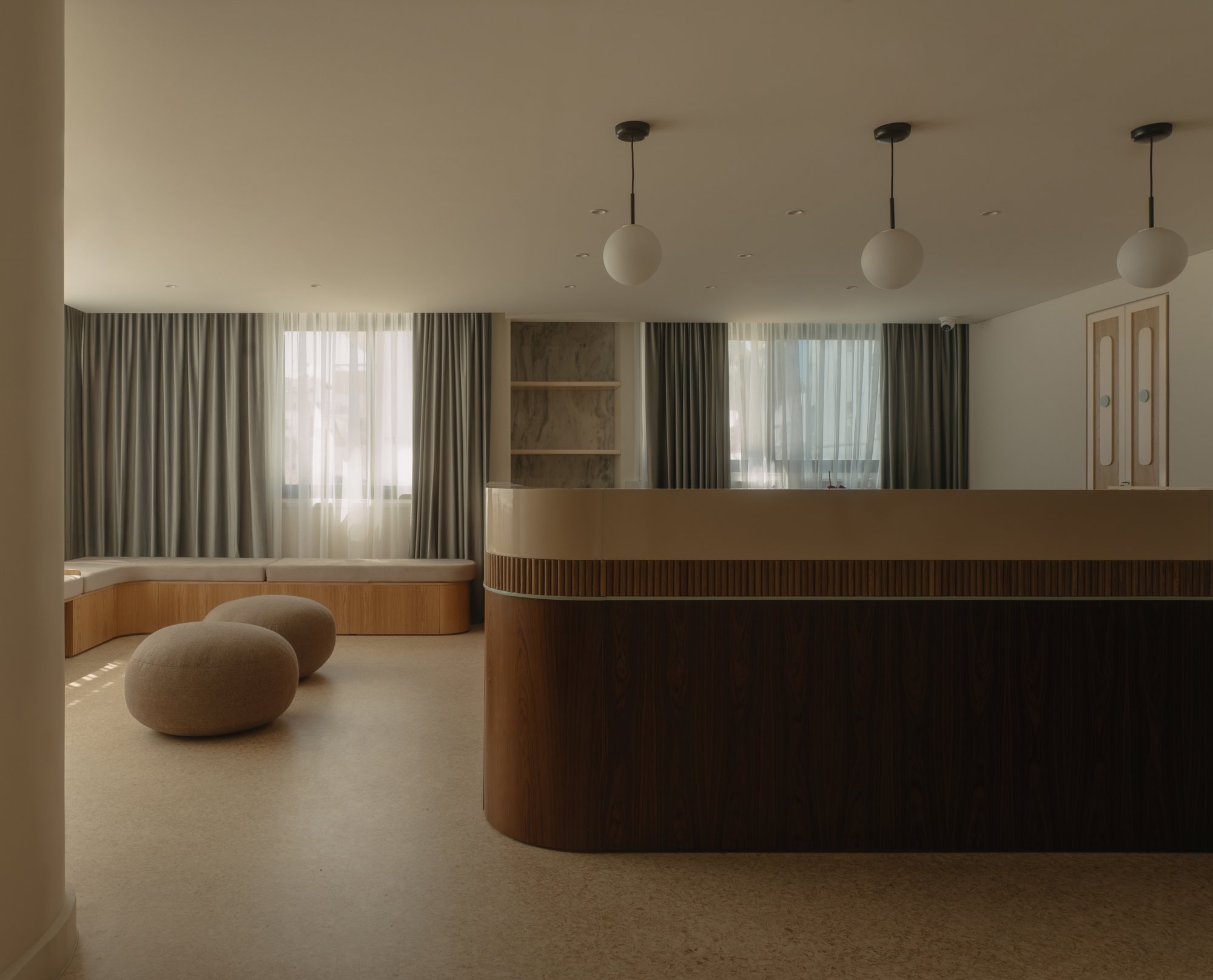 Reception space with built-in oak seating and stone pouffes