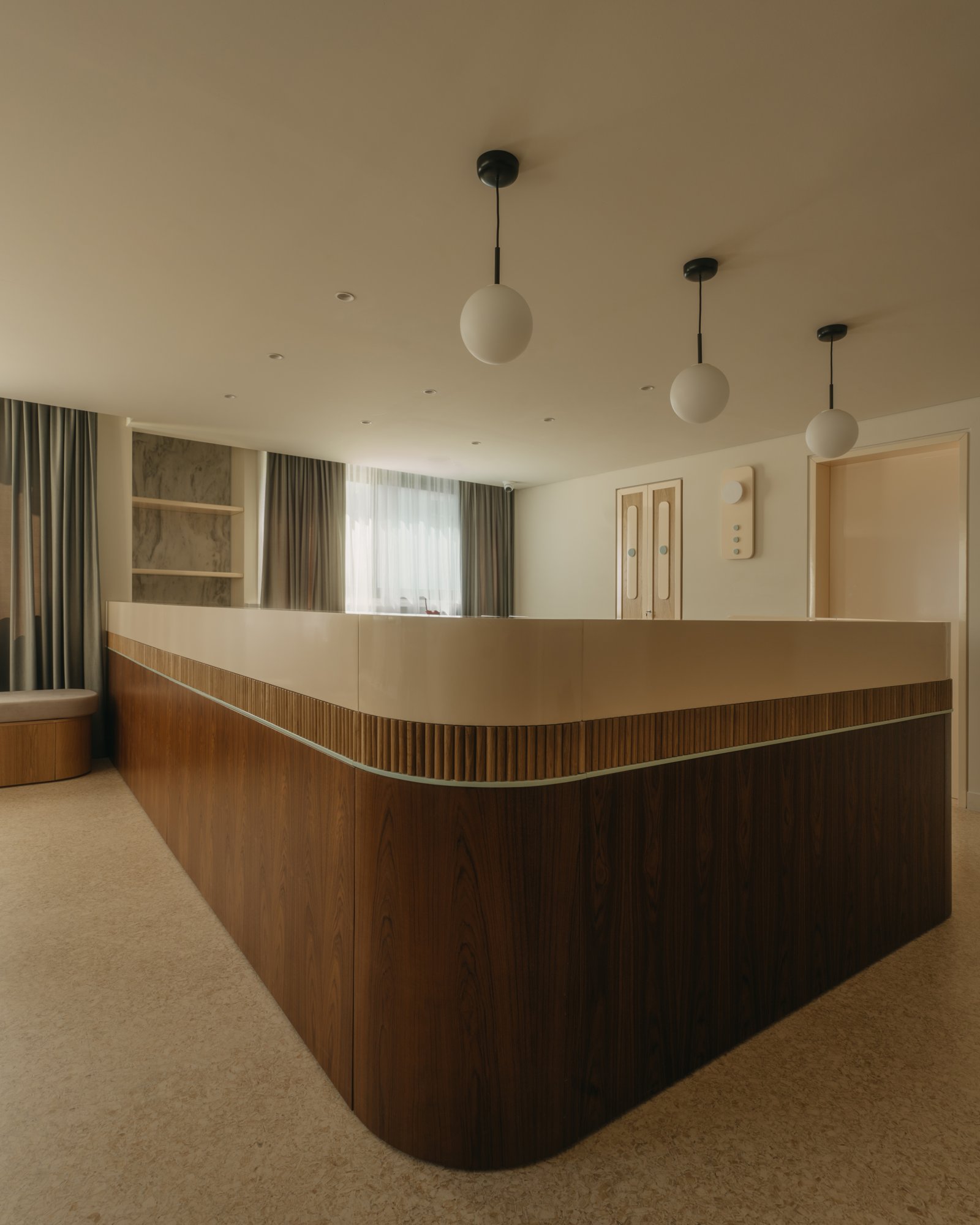 Curved walnut and fluted oak reception counter in warm tones