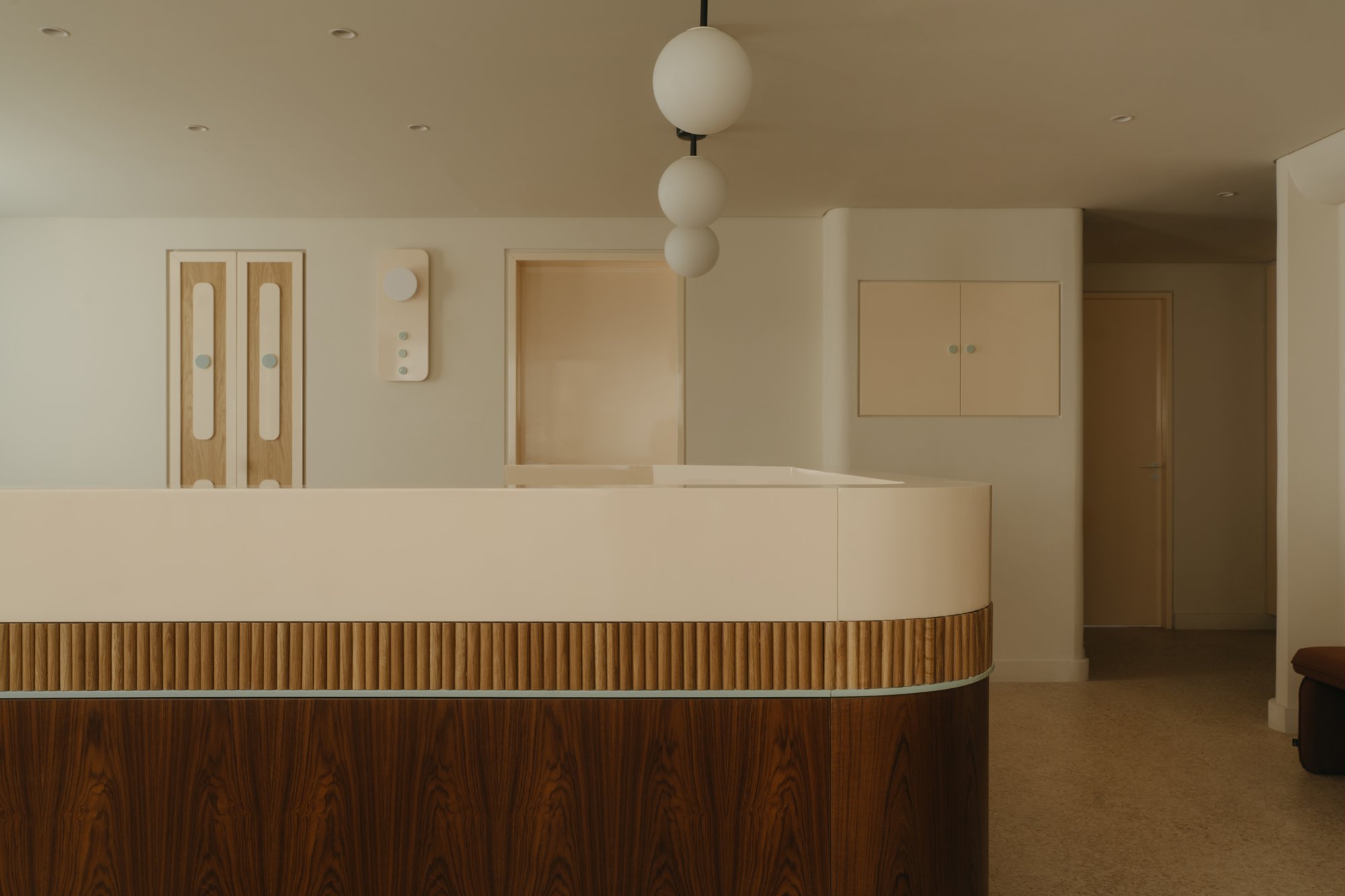 Curved reception counter in walnut and fluted oak with pendant lighting