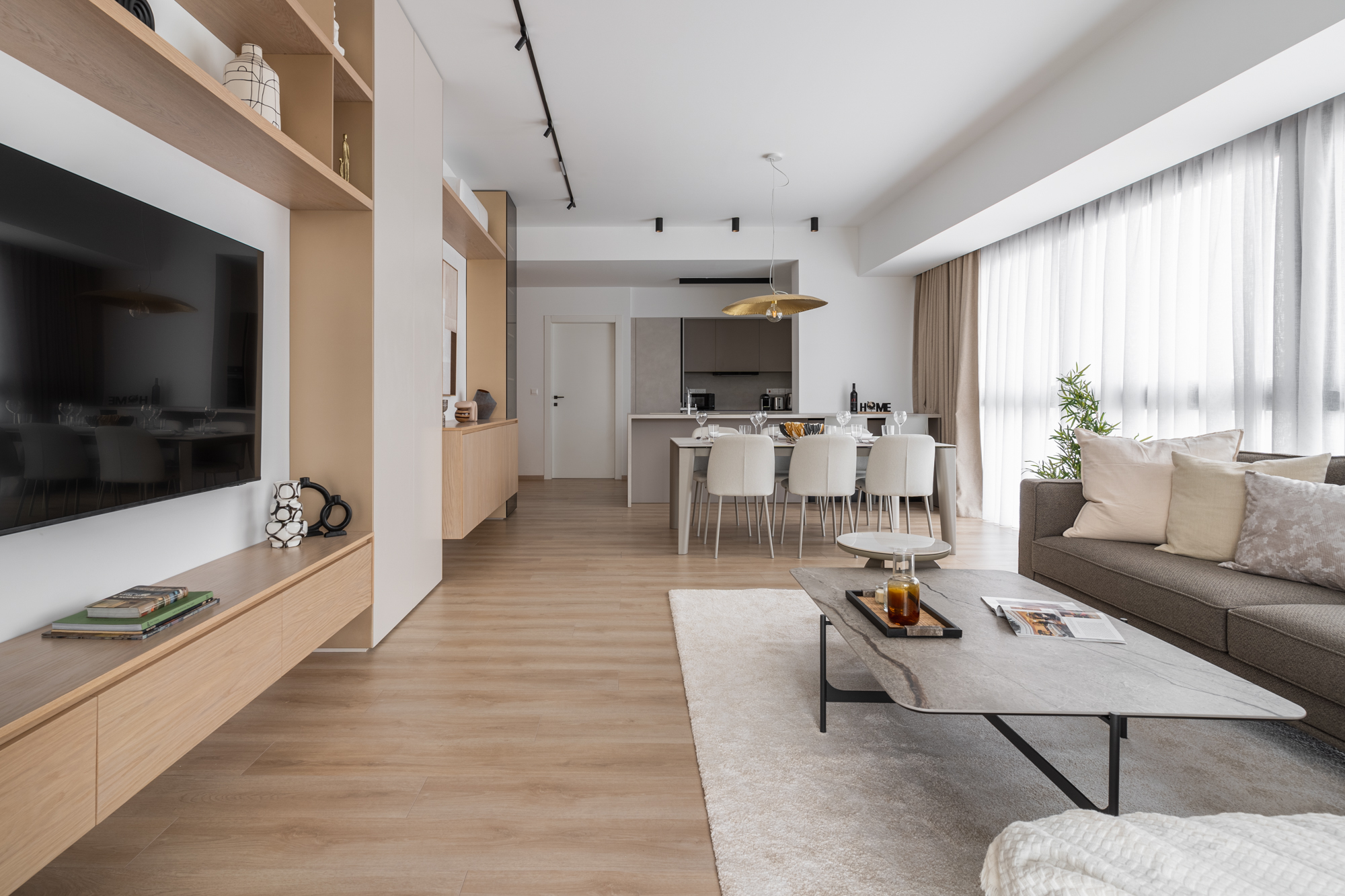Living, dining and kitchen framed by an oak media wall